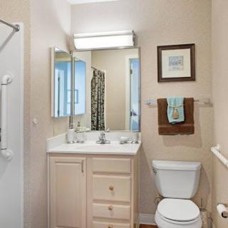 A well-lit and organized bathroom featuring a shower, vanity, and decorative towels.