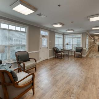A bright and inviting lobby area with wooden floors, featuring comfortable seating and large windows.