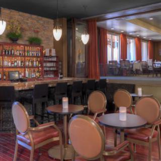A cozy restaurant and bar with a warm interior design, featuring seating areas and a well-stocked bar.