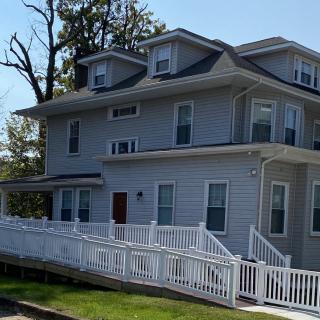 A two-story suburban house with a white exterior and a surrounding fence.