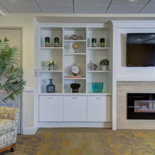 A cozy living room with a shelving unit, fireplace, and television.