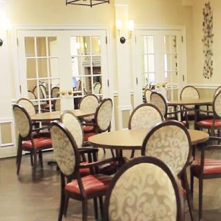 A cozy dining room area with elegantly arranged tables and chairs, featuring soft lighting and tasteful decor.