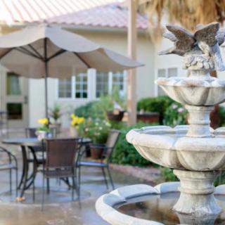 A serene outdoor patio with a decorative fountain and seating area.