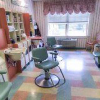 A brightly lit salon with chairs and a mirror near a large window.