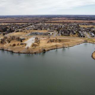 Aerial view of a tranquil lake surrounded by suburban developments and natural landscapes.