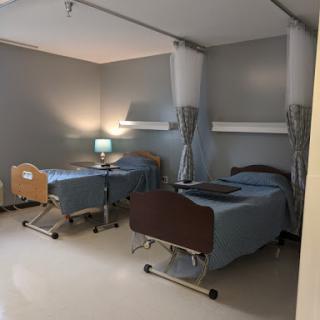 A view of a shared patient room in a healthcare facility, featuring two hospital beds and basic furnishings.