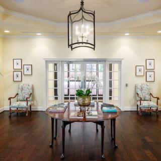 A traditionally decorated living room with elegant furnishings, including a central table, chairs, and a chandelier.