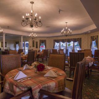 An elegant dining room with neatly set tables and chandeliers.