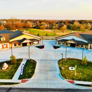 An aerial view of a suburban area with buildings, parking lots, and surrounding greenery.