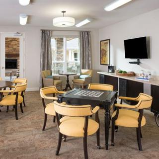 A modern dining room with yellow chairs, tables, a wall-mounted television, and large windows.