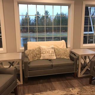 A cozy living room with a loveseat and a large window view.