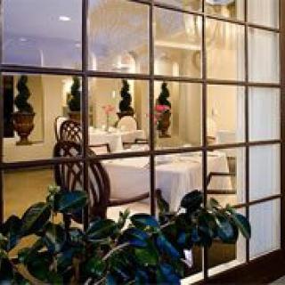 Elegant dining area viewed through a window with decorative plants.