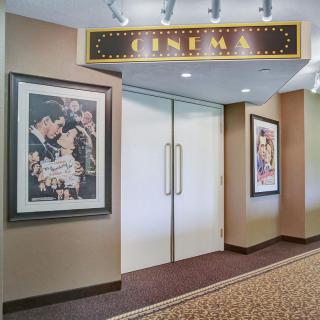 The entrance to a cinema, featuring movie posters on the walls and a sign above the doors.