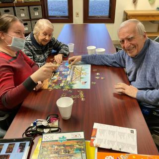 A group of people enjoying a puzzle together at a table.