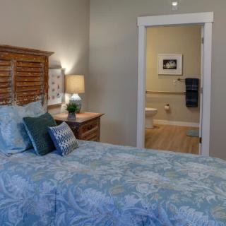 A cozy bedroom with a view into the bathroom through an open doorway.