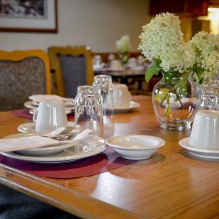 A beautifully set dining table with plates, glasses, and a vase of flowers in a restaurant setting.