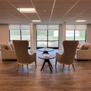 A cozy lounge area featuring modern furniture, with large windows allowing natural light to fill the space.