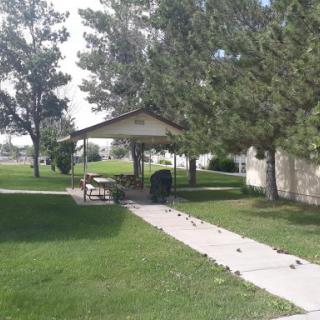 A peaceful park area featuring a gazebo surrounded by lush greenery and a pathway.
