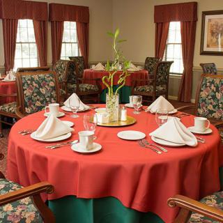 A beautifully set dining table with red tablecloths and elegant folded napkins in a formal restaurant setting.
