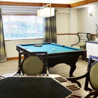 A cozy game room featuring a billiard table and elegant seating.