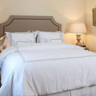 A cozy bedroom with a neatly made bed and a bedside lamp.