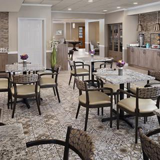 A modern cafe interior with tiled flooring and neatly arranged tables and chairs.