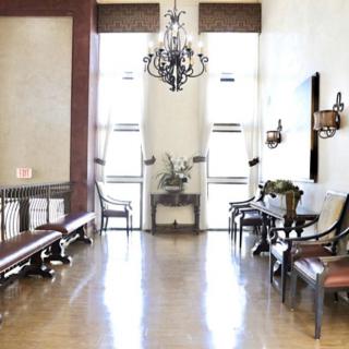 A spacious hallway with antique furnishings and a chandelier.