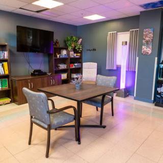 A modern workspace featuring a table and chairs, equipped with shelves and a television for meetings.