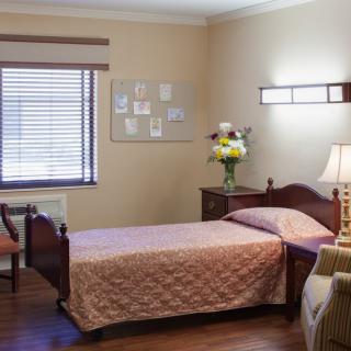 A cozy and neatly arranged bedroom with a single bed, soft lighting, and tasteful decor.