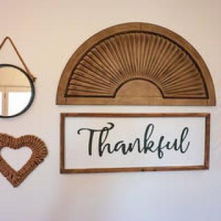 A cozy wall arrangement featuring a thankful sign, a heart-shaped frame, and a decorative mirror.