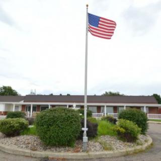 A building with an American flag flying on a flagpole surrounded by landscaping.