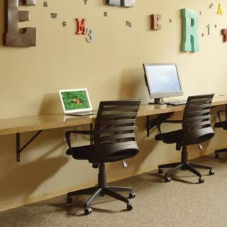 A modern office setup with two computers and chairs against a decorated wall.