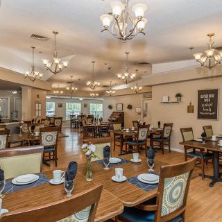 A spacious and elegantly decorated dining room with multiple tables and chandeliers.