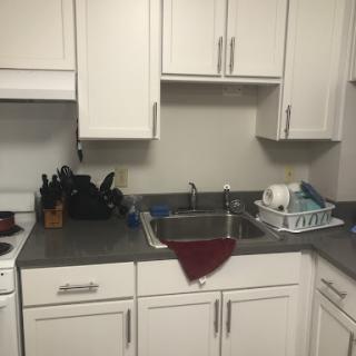 A clean kitchen with white cabinetry, a sink, and neatly arranged utensils.