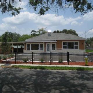 A suburban house with a fenced yard under a partly cloudy sky.
