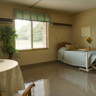 A well-lit hospital room with a single bed, table, and window.