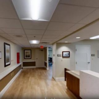 A view of an office hallway with a reception desk and artwork on the walls.