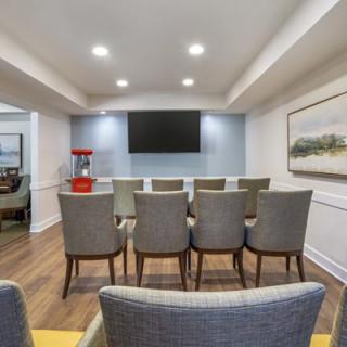 A well-organized conference room with rows of chairs facing a large screen and a popcorn machine on the side.