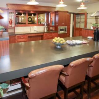 A modern kitchen with a spacious countertop, bar stools, and stylish lighting.