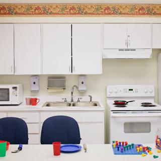 A kitchen setup with cabinets, a sink, microwave, stove, and colorful dishes.