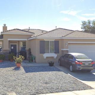 A suburban house with a car parked in the driveway on a sunny day.