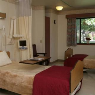 A hospital room with twin patient beds and medical equipment.