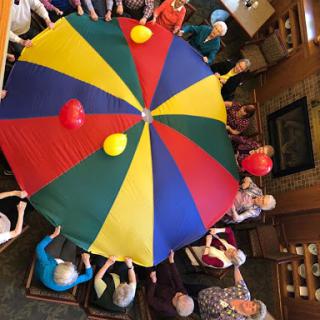 A lively group of senior citizens enjoying a fun parachute activity together.