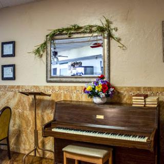 A beautifully arranged corner featuring a classic piano, decorated with a floral arrangement and a framed mirror.
