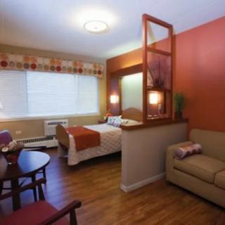 A cozy hotel room with a bed, sofa, and dining area.