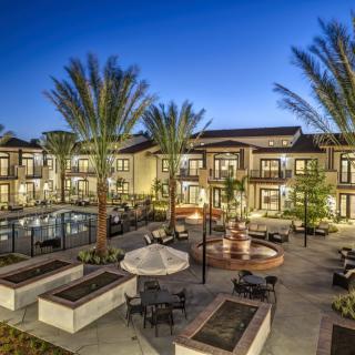 A luxurious resort with a pool and outdoor seating area, beautifully lit at night.