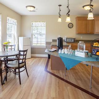 A well-lit kitchen and dining area featuring a table with chairs, hardwood flooring, and a beverage station.