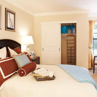 A cozy, tastefully decorated bedroom with a neatly made bed and sliding closet doors.
