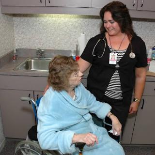 A nurse providing care to an elderly patient in a medical office.