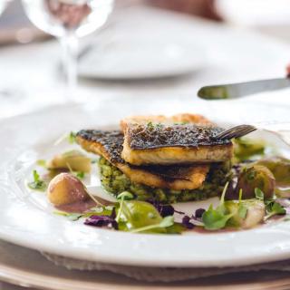 A gourmet fish dish served with a side of fresh vegetables at a restaurant.